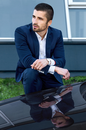 handsome man near the car on a background of cityscapeの写真素材