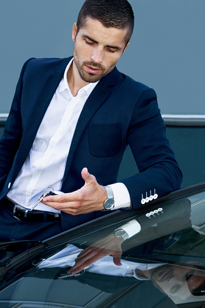handsome man near the car on a background of cityscapeの写真素材