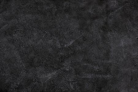 black wall covered with a layer of uneven rough plasterの写真素材