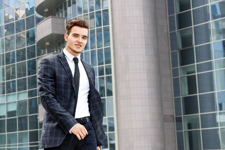 man smiles and walks past the windows of high-rise buildingsの写真素材