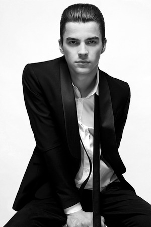 Attractive young business man looking at the camera, white background vertical shotの写真素材