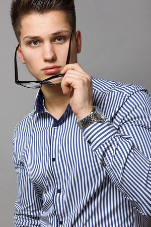 young men in a striped shirt off his glassesの写真素材