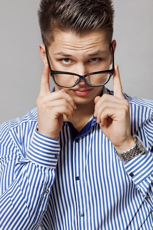 young men in a striped shirt off his glassesの写真素材