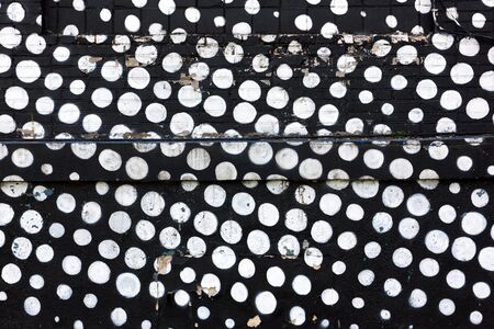 White circles on a black brick wall graffitiの写真素材