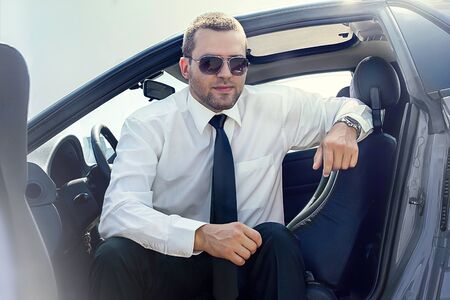 handsome man sitting in a gray blue carの写真素材
