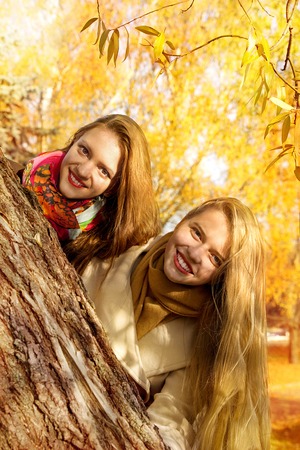 two girls are walking in the autumn parkの写真素材