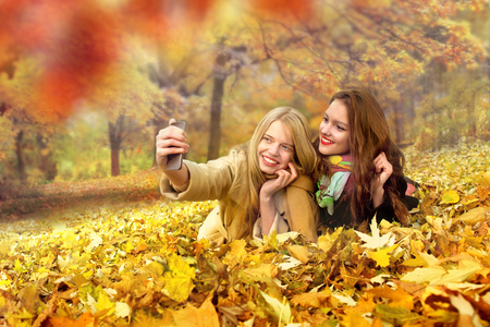 Friends taking selfie at beautiful autumn day in the park, outsideの写真素材