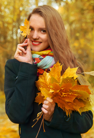 girl is standing with a bouquet of autumn leavesの写真素材