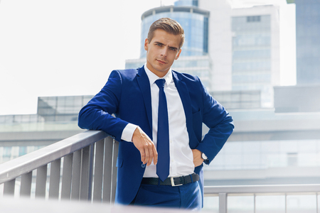 A man in a blue suit against a background of dark modern architectureの写真素材