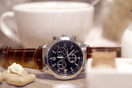 Mens watch next to a cup of coffeeの写真素材