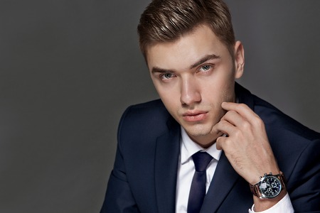portrait of a man sitting with a suit with a watch, studioの写真素材