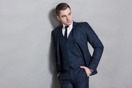 man in blue suit with vest in studio on gray backgroundの写真素材