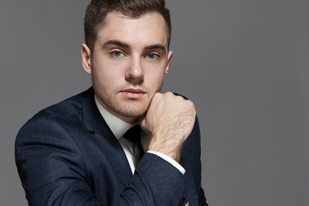 close-up portrait of a man in a blue suit with a vest in the studio on a gray backgroundの写真素材