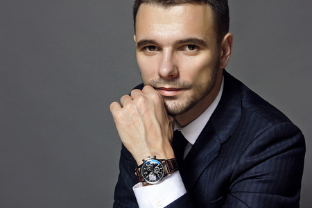 portrait of a man sitting with a suit with a watch, studioの写真素材