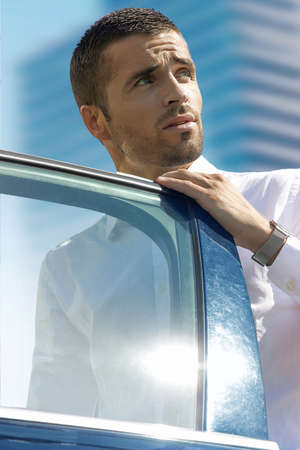 on a sunny day near the business center a serious man sits down in the car and looks upの写真素材