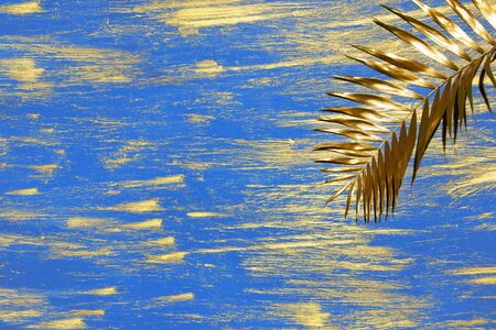 decorative blue background with golden smears paint and palm branchの写真素材