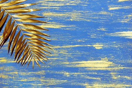 decorative blue background with golden smears paint and palm branchの写真素材