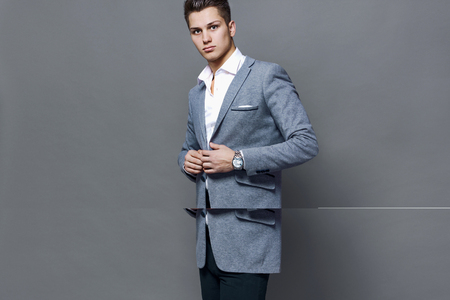 Elegant young handsome man in stylish gray jacket. Studio fashion portrait.の写真素材