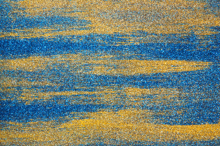 The smears of blue and gold paint are randomly scattered over the backgroundの写真素材