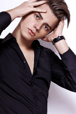 the guy in a black shirt unbuttoned beautifully straightens hair with both handsの写真素材