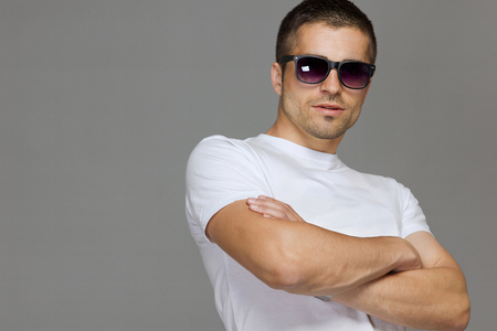man in sun glasses, in white cotton t-shirt closeup on gray backdrop. Modern garment front view. Textile design.の写真素材