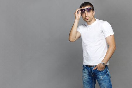 guy in a white T-shirt holding sunglasses, isolatedの写真素材