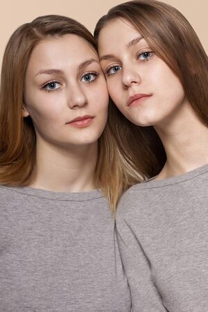 twin sisters posing on a light-beige background, studioの写真素材