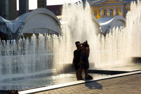 Couple on the background of a city fountain. Summer heat. sunny dayの写真素材