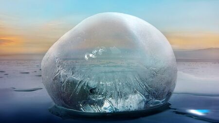 Transparent blue ice on the background of an endless snow landscape during sunset. Winter timeの写真素材