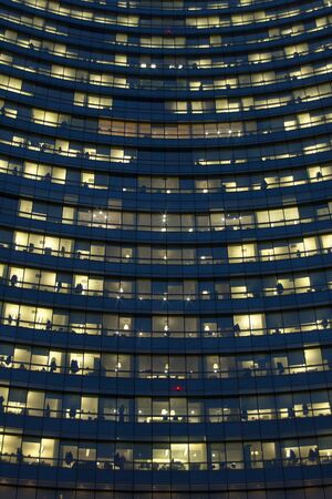 office facade with luminous yellow windows late at nightの写真素材