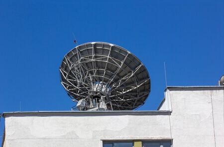 Metal reflector dish in action on the roof of an office buildingの写真素材