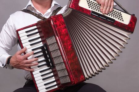 Closeup detail of hands playing a red accordion instrumentの写真素材