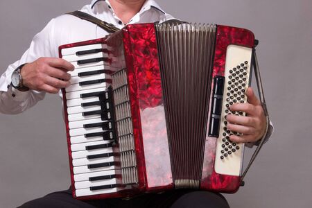 Closeup detail of a man in a white shirt playing the red accordion. Hands close-upの写真素材