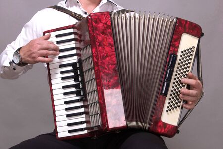 Closeup detail of hands playing a red accordion instrumentの写真素材
