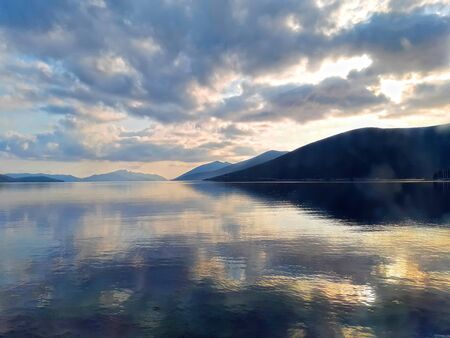 yellow-blue seascape with hills and cloudsの写真素材