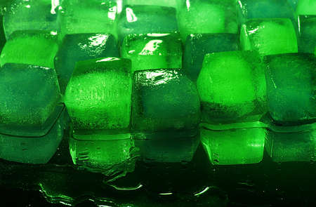 Green, emerald ice cubes lies on a black background.の写真素材