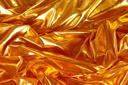 Fortune's Gold is the color trend of 2021. Shiny, silk fabric lying in soft folds, top view.の写真素材