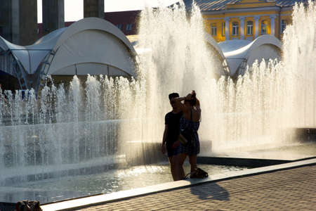 Couple on the background of a city fountain. Summer heat. sunny dayの写真素材