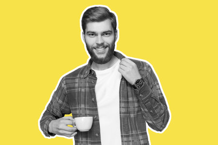 Young man in casual plaid shirt isolated. Holds a cup in his hand on a trendy yellow backgroundの写真素材