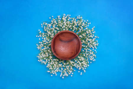 For photos of newborns, background. Digital backgrounds for newborns. Wooden dish on a blue background with fur inside, surrounded by lily of the valley flowers.の写真素材