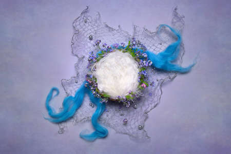 Digital backgrounds for newborns. Wooden basket with white fur on a blue background in a net and pearlsの写真素材