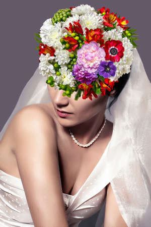 Bride with floral hairstyle. Woman with a bouquet on her head. Vogue style portrait.の写真素材