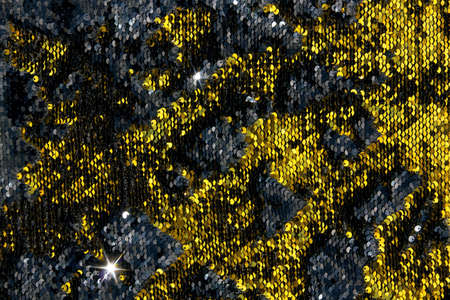 Yellow metal sequins background. Fabric background with black and gold iridescent sequinsの写真素材