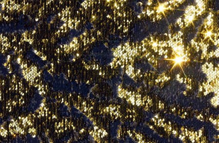 Yellow metal sequins background. Fabric background with black and gold iridescent sequinsの写真素材