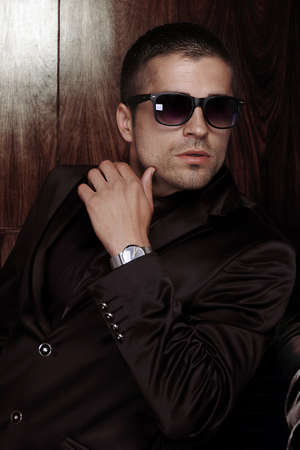 a man sitting with wrist watch on dark background. Male beauty, fashion.の写真素材
