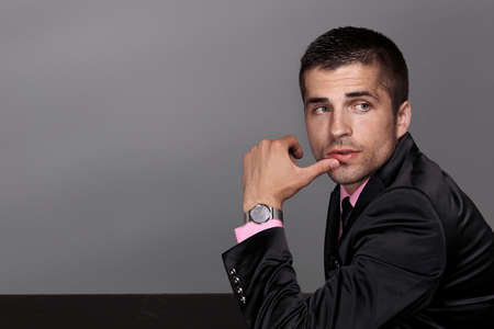 Man in black suit with watch, half-length portrait, studio fashion portraitの写真素材