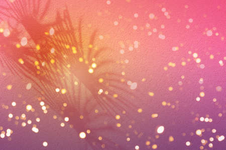 Pink shadow of fan palm leaves on a light purple wall. Tropical holiday background.の写真素材