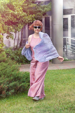 Mature plus size woman walks in the park in overalls in summer, trendy set of clothes. Urban summer fashion.の写真素材