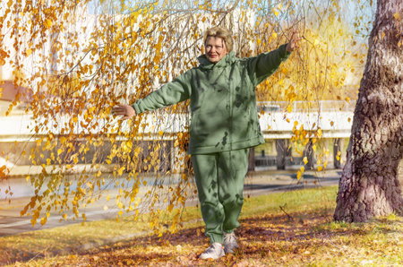 Mature woman in a green sweatshirt on a walk in the autumn park. Digital detox, sports.の写真素材