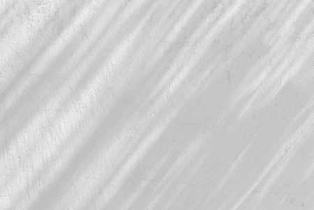 Gray shadow of natural leaves tree and tree trunk falling on white concrete wall for background design and wallpaperの写真素材